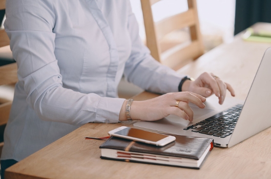 Mujer en escritorio escribiendo en un ordenador portátil
